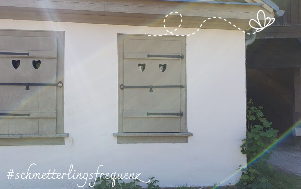 weißes Gebäude mit 2 verschlossenen Fensterläden mit Herzöffnungen